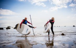 Couple holding paddleboards on the Isle of Wight